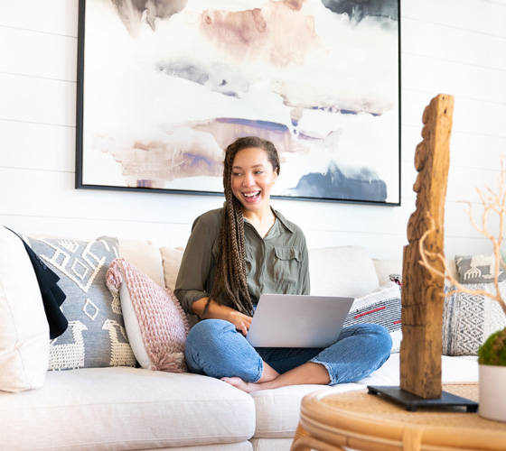 woman smiling while using computer on couch