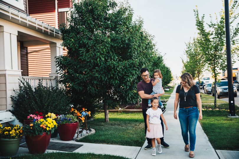 Family walking in front of homes and flowers at The Orchards in Edmonton, AB by Brookfield Residential