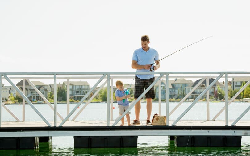 A Father and son fishing off a bridge into Auburn Bay Lake in Calgary