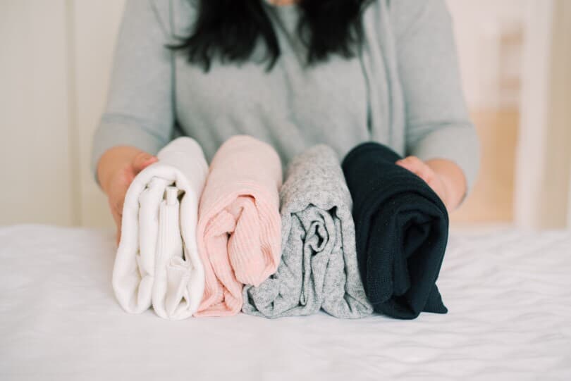 A woman organizing clothing in a variety of colours