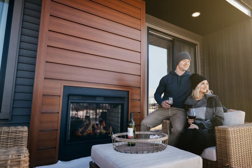 Couple enjoying wine by an outdoor fireplace in the Brookfield Residential home in Edmonton, AB