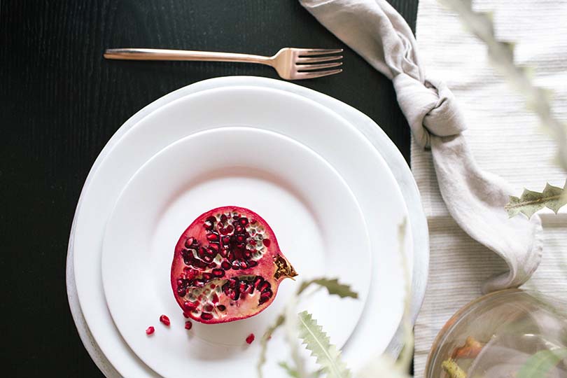A half of a pomegranate displayed on a dinner plate