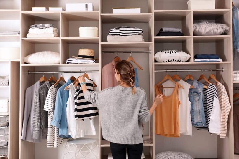 Woman hanging up a shirt in an organized closet