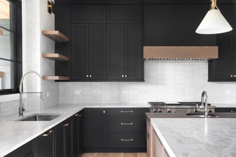 A luxury kitchen with black cabinets and tile backsplash