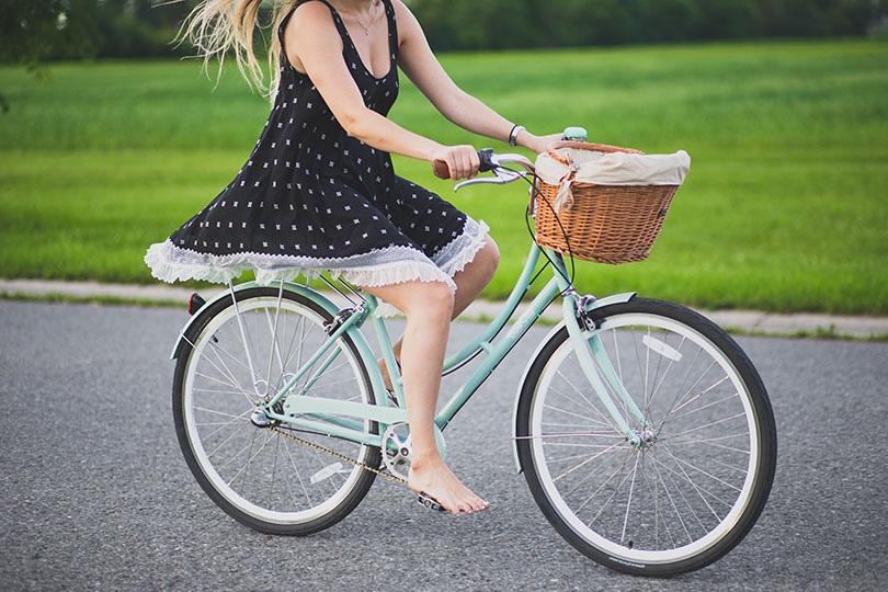 Girl in dress riding bike barefoot