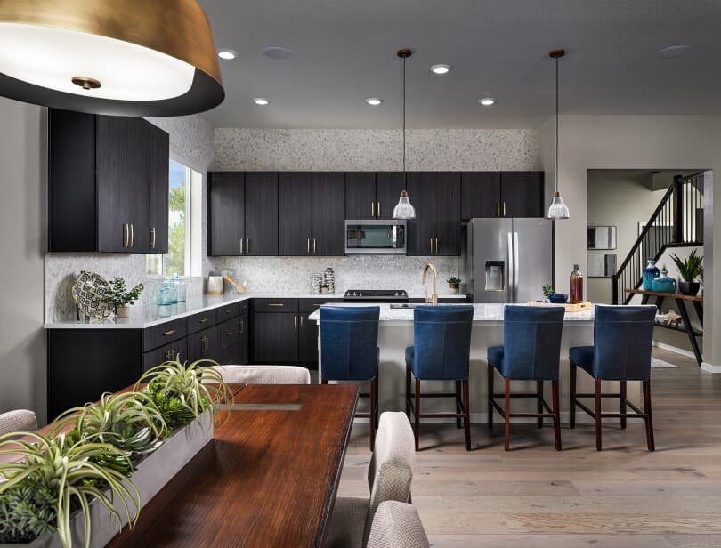 Kitchen with dark cabinets and blue chairs at the island at Barefoot Lakes in Firestone, Colorado