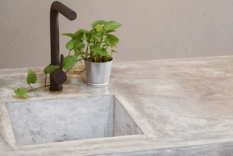 Concrete countertop with black faucet and small plant