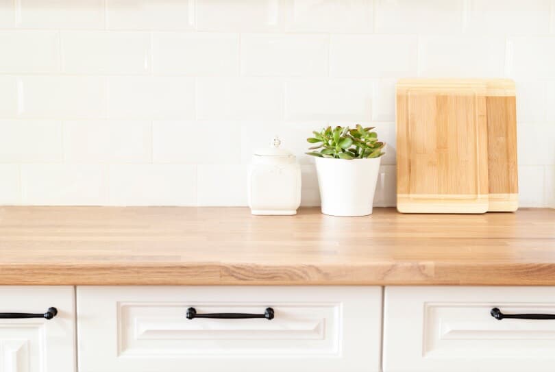 Wood butcher block countertop in a kitchen with white cabinets