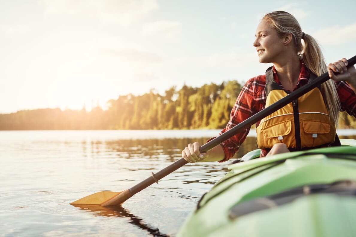 Woman kayaking on a lake as the sun is setting
