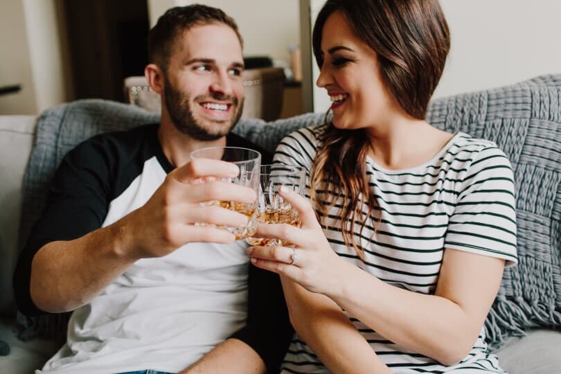 Couple cheersing with drinks on a couch